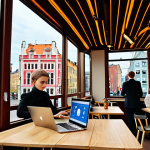 **Prompt 1:** A vibrant and dynamic cityscape of Riga, Latvia, showcasing a striking contrast between ornate Art Nouveau historic buildings and sleek, modern glass skyscrapers. In the foreground, digital nomads are working on laptops in a stylish cafe, while well-dressed corporate professionals walk briskly near newly developed business districts. A subtle hint of the European Union flag or euro currency symbol is visible, emphasizing stability and growth. The scene is bathed in bright daylight, conveying an atmosphere of prosperity and forward momentum, with a mix of historical charm and contemporary progress.